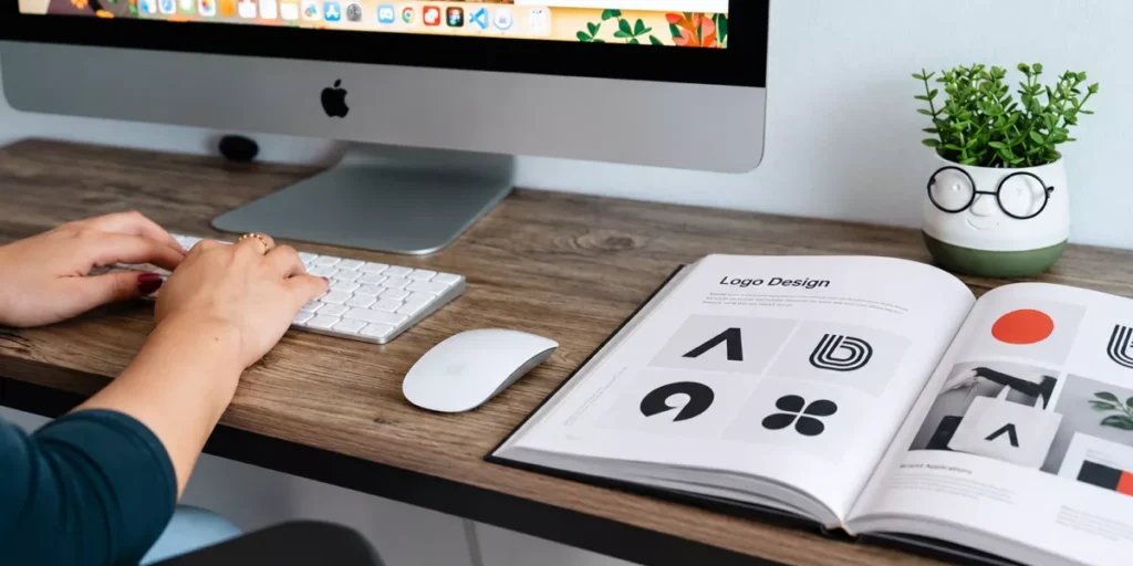 Logo sketches and colour swatches beside a laptop showing a website design